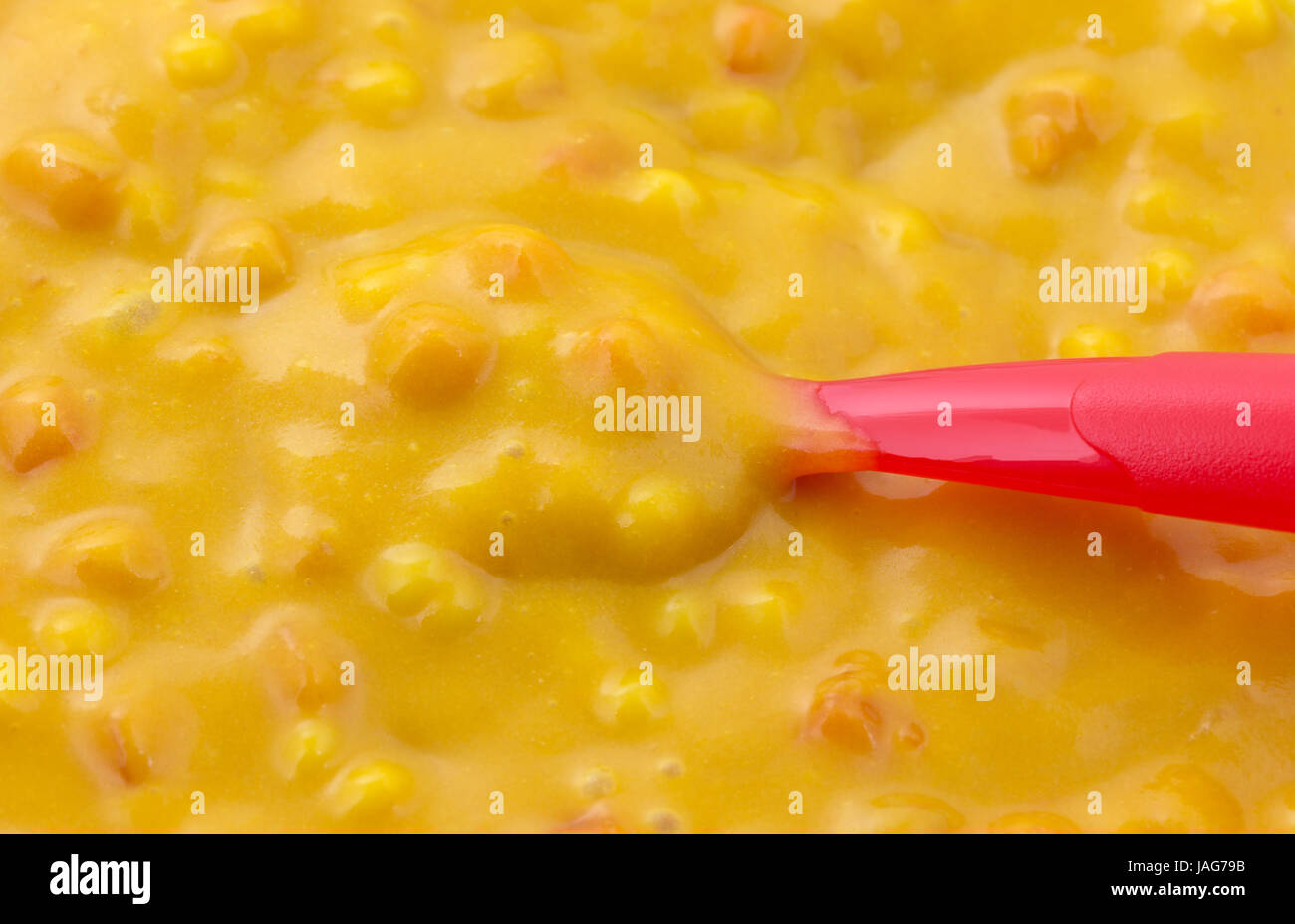 Vista ravvicinata di maccheroni e formaggio cibo per bambini con un piccolo rosso in plastica cucchiaio. Foto Stock