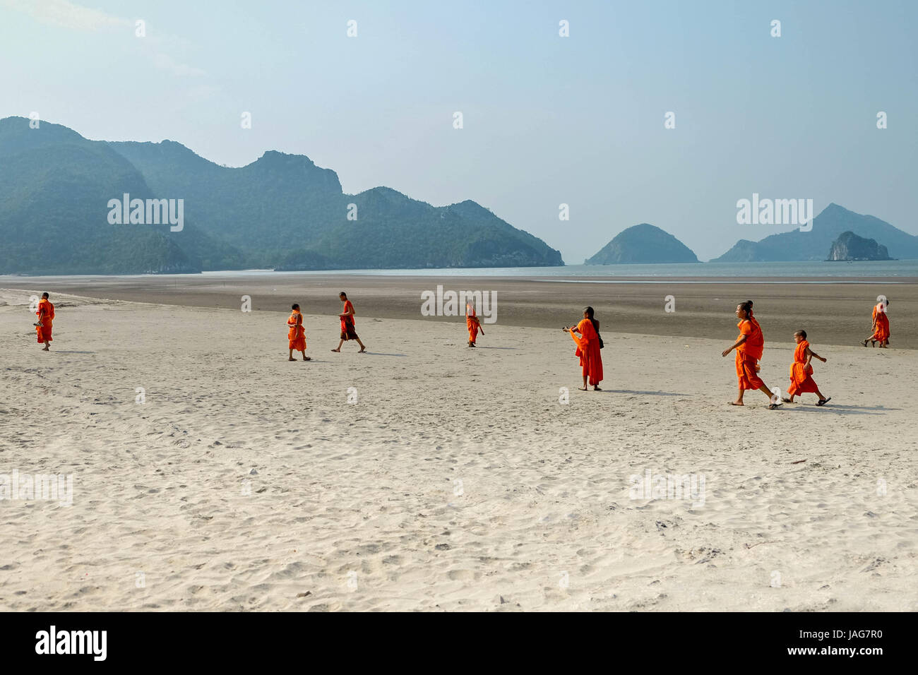 Scenario Theravada tailandese i monaci buddisti e il debuttante in giallo arancione abiti dello zafferano su una spiaggia di sabbia con gradini, montagne e natura tutto Foto Stock