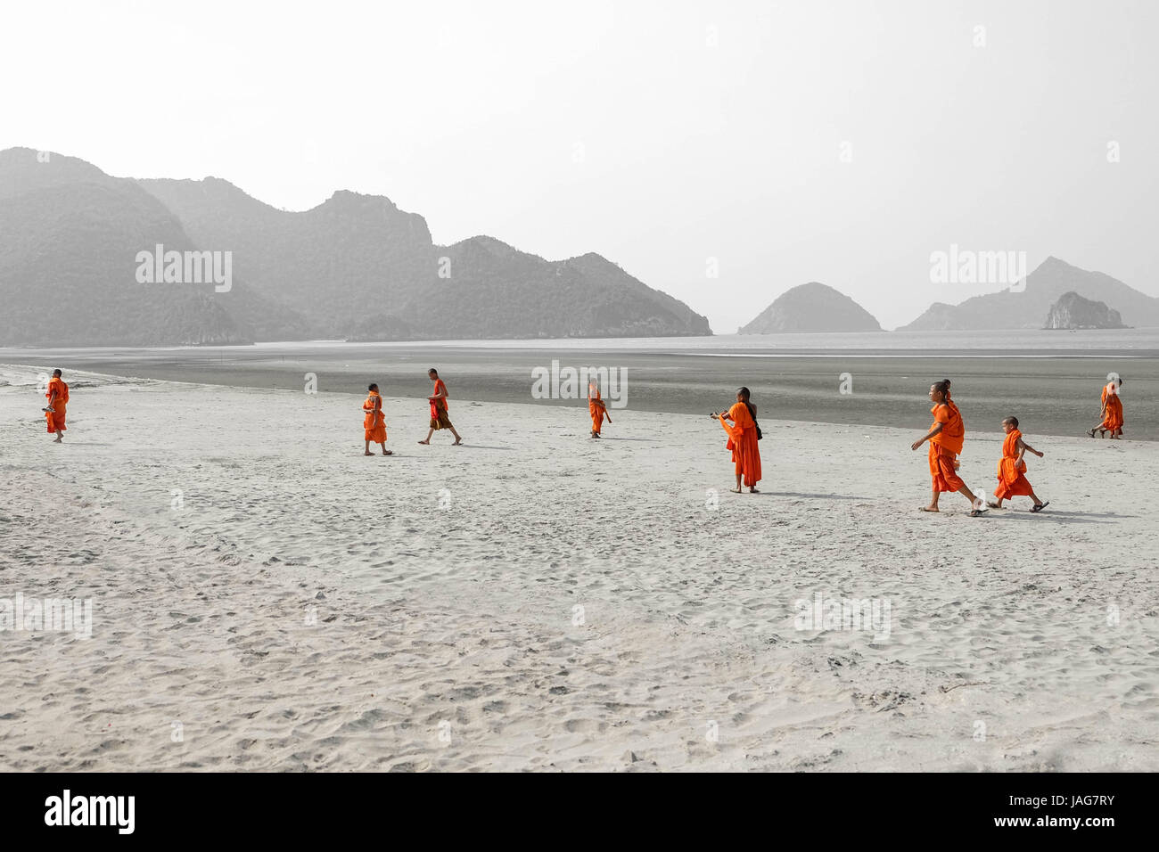 Scenario Theravada tailandese i monaci buddisti e il debuttante in giallo arancione abiti dello zafferano su una spiaggia di sabbia con gradini, montagne e natura tutto Foto Stock