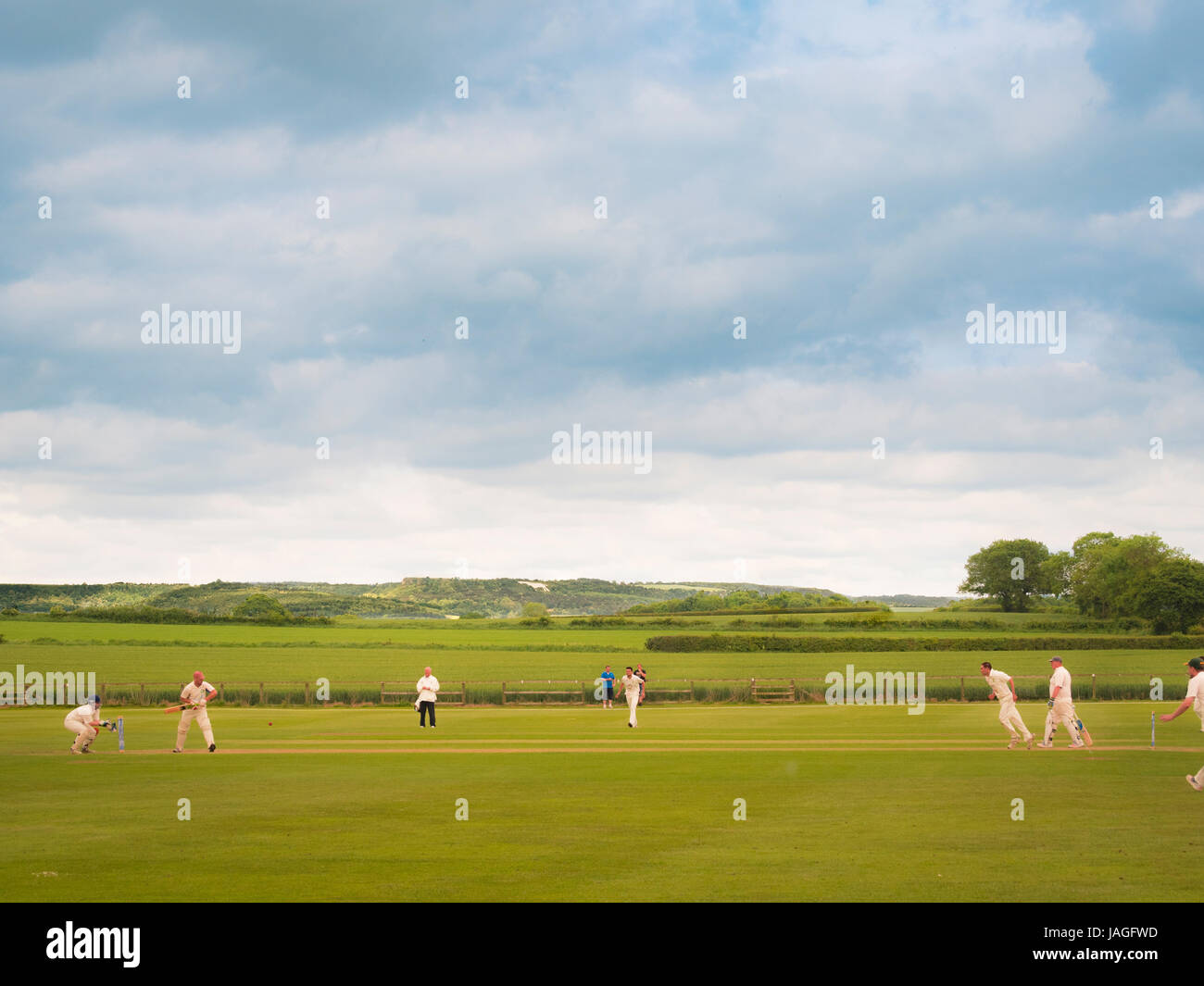 Partita di Cricket di essere riprodotti in un tipico villaggio inglese di Sessay con il cavallo bianco in background. Foto Stock