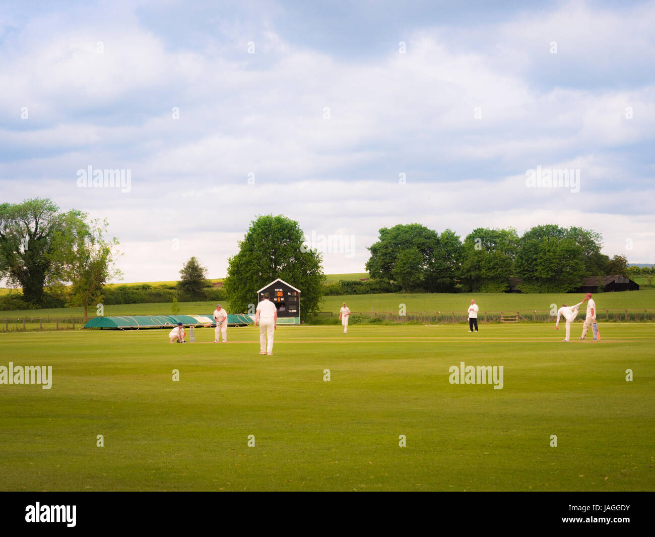 Partita di Cricket di essere riprodotti in un tipico villaggio inglese. Foto Stock