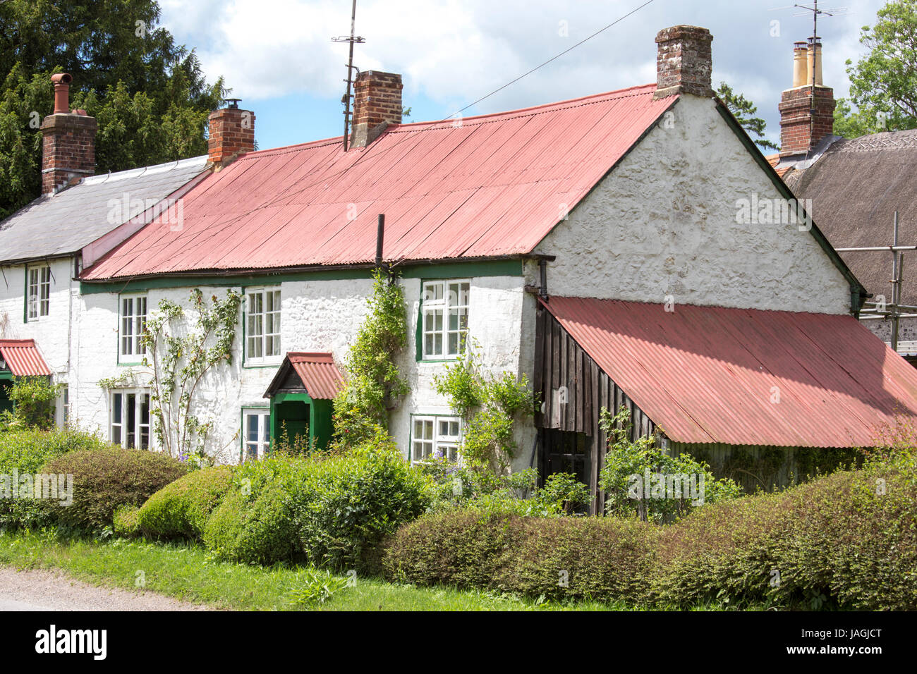 Cottage con acciaio tetti ondulato in West Sussex village, England, Regno Unito Foto Stock