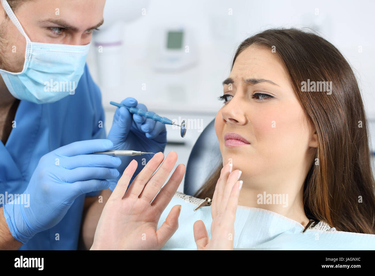 La paura di un paziente con un medico tenta di esaminare la sua in un studio dentistico Foto Stock