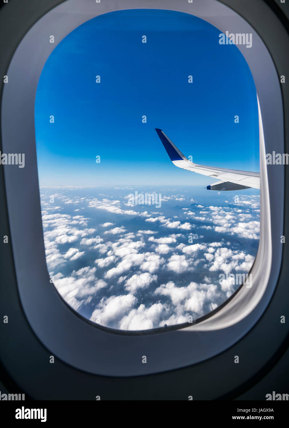 Vista attraverso il finestrino di un aereo di passeggero volare al di sopra bella bianco delle nuvole in cielo Foto Stock