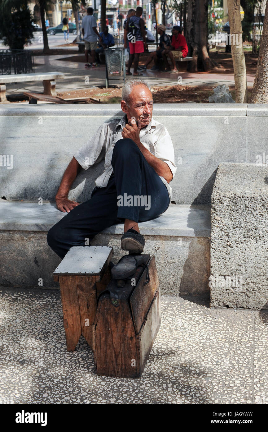 Shoeshiner tubazione di fumare in attesa per i clienti nella Vecchia Havana, Cuba Foto Stock