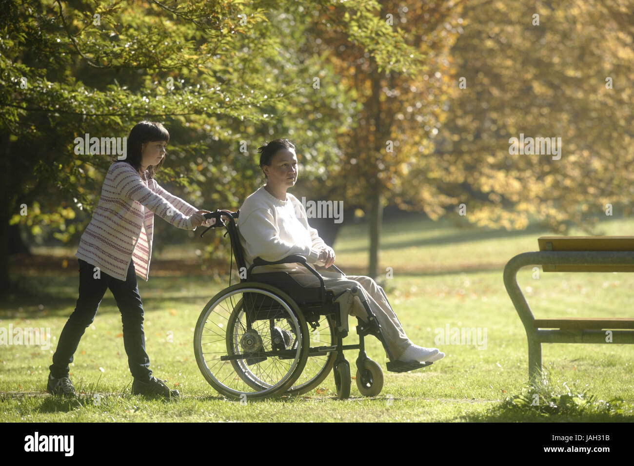 Ragazza spinge la donna a valida la sedia a rotelle, Foto Stock
