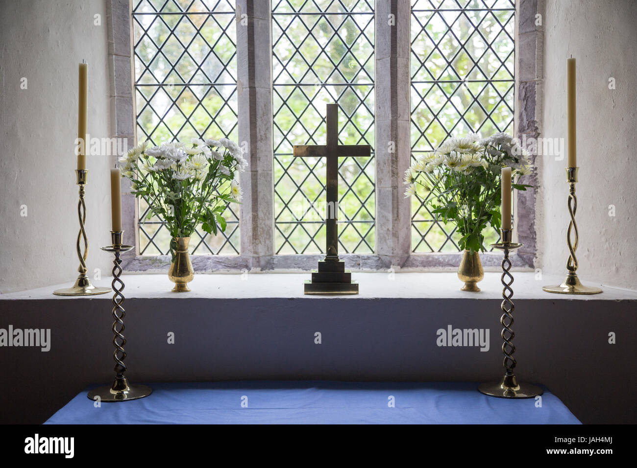Una croce cristiana, fiori e candele in Llanhowel la finestra della chiesa nel tempo pasquale in zone rurali del Galles Foto Stock