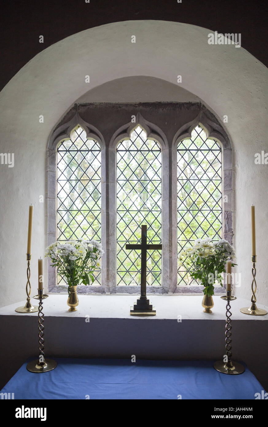 Una croce cristiana, fiori e candele in Llanhowel la finestra della chiesa nel tempo pasquale in zone rurali del Galles Foto Stock