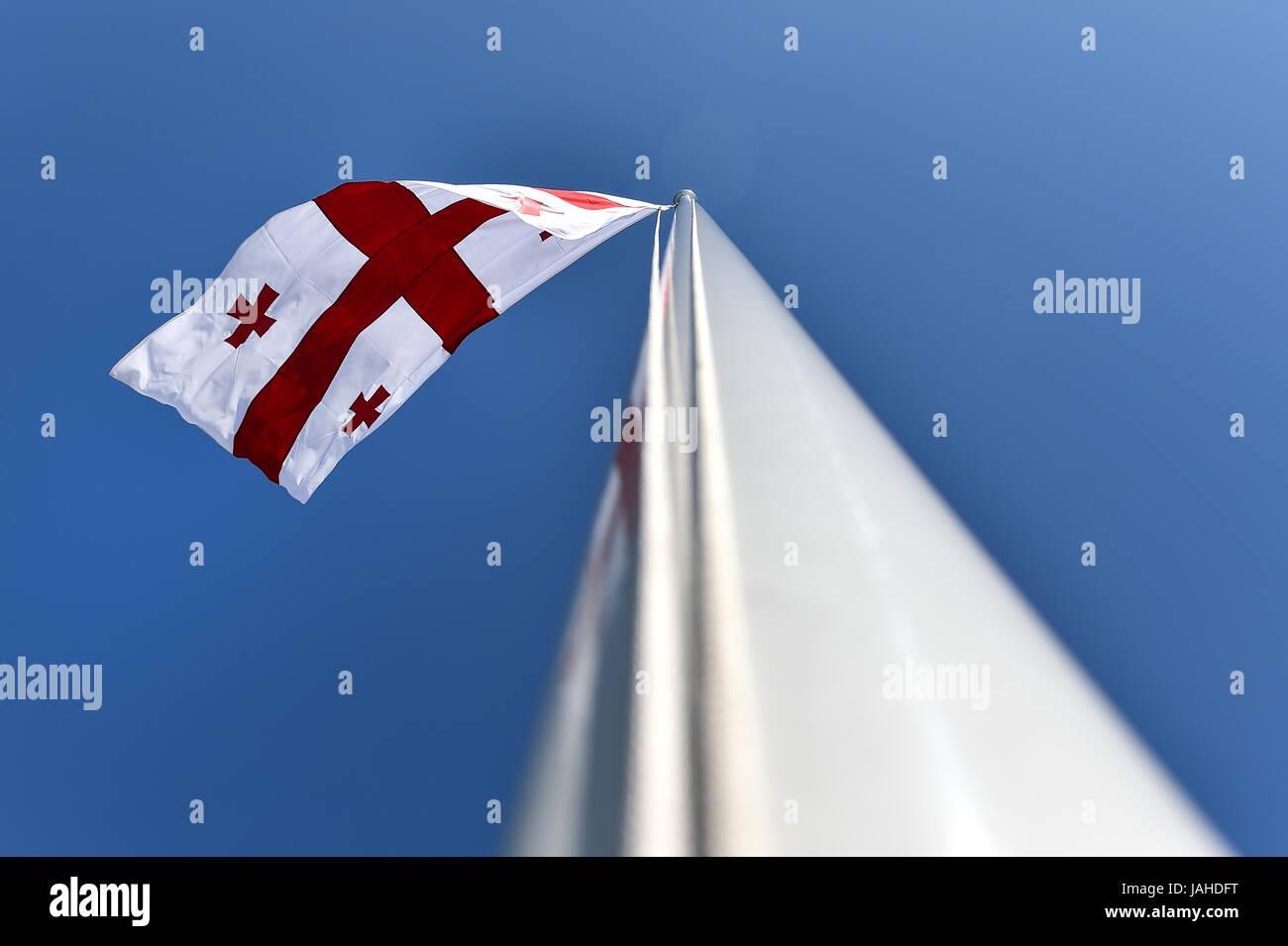 La Georgia bandiera nazionale soffiata dal vento contro un cielo blu Foto Stock