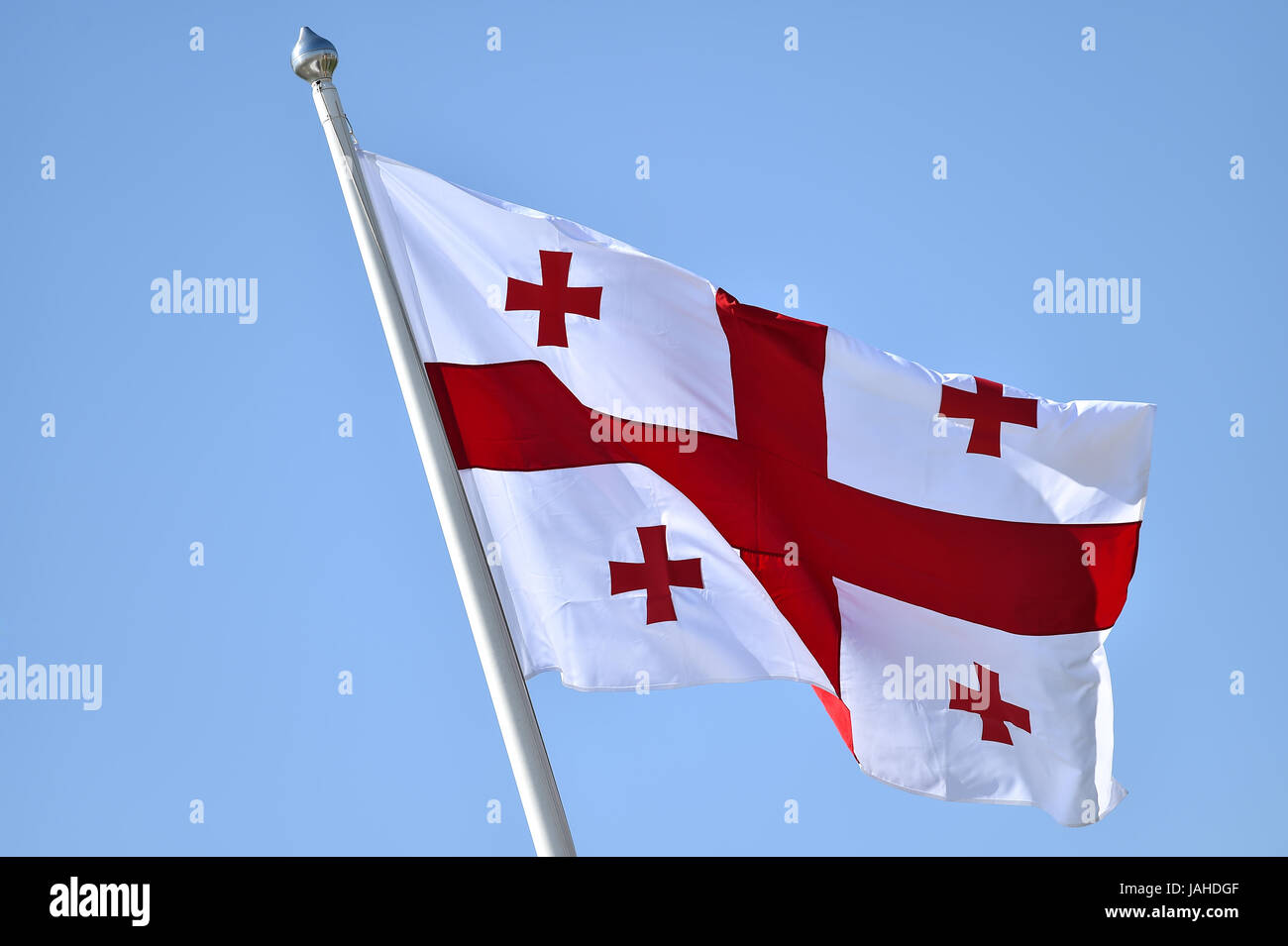 La Georgia bandiera nazionale soffiata dal vento contro un cielo blu Foto Stock