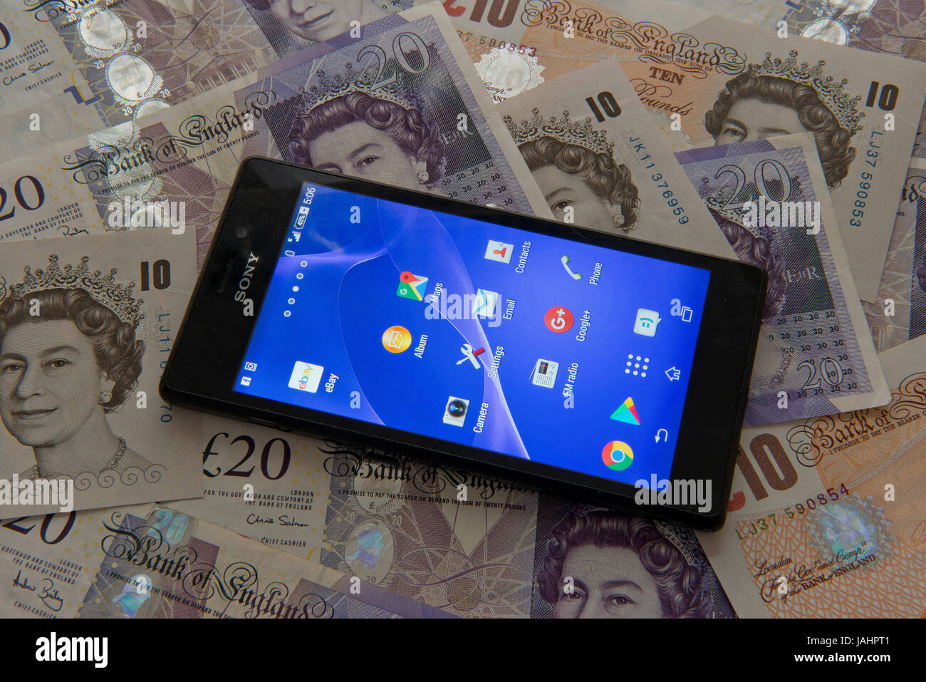 Un mobile (android) telefono su uno sfondo di valuta britannica Foto Stock