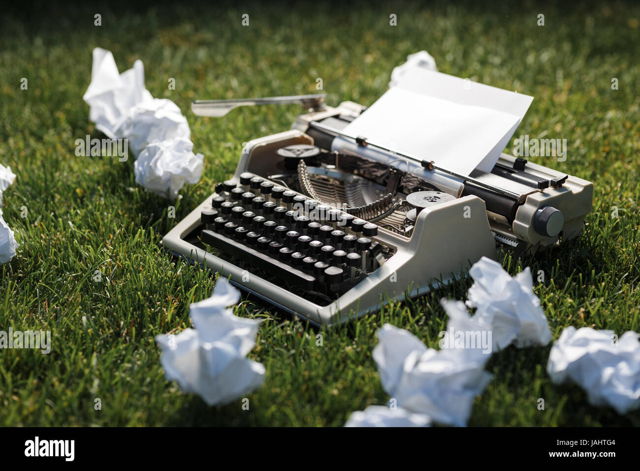 Foto della vecchia macchina da scrivere su un prato verde con un foglio di carta. Foto Stock