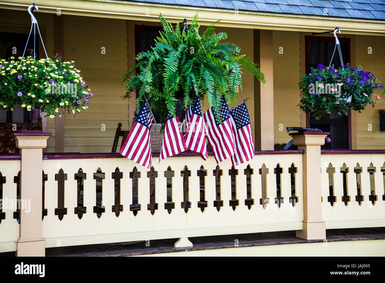 Bandiere americane su un portico anteriore della casa con le piante appese, contea di Cape May, New Jersey, bandiera degli Stati Uniti 2017, piante dei cestini appesi dell'America Foto Stock
