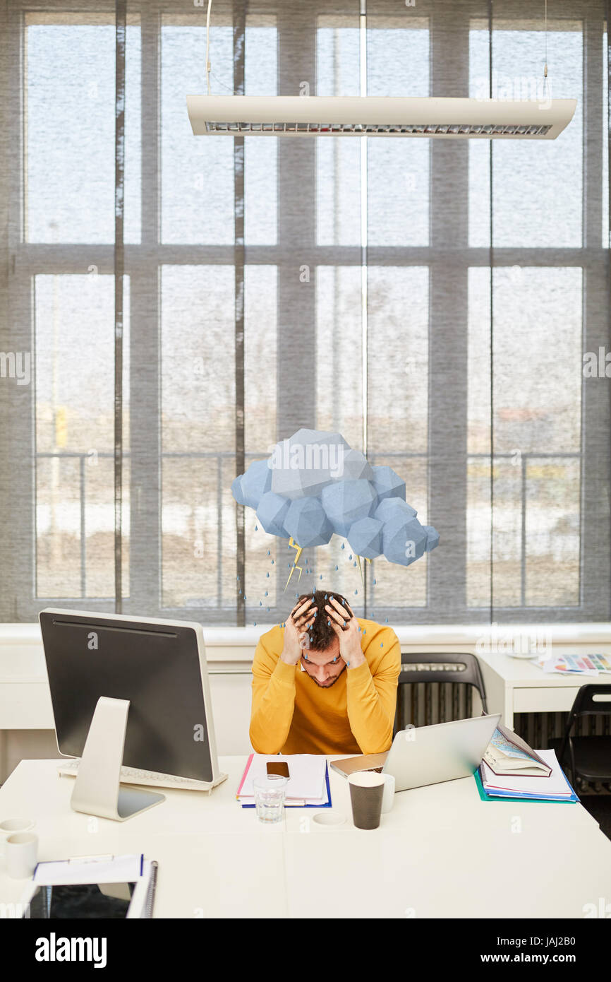 Manager con Burnout e nube di pioggia sopra la sua testa in office Foto Stock