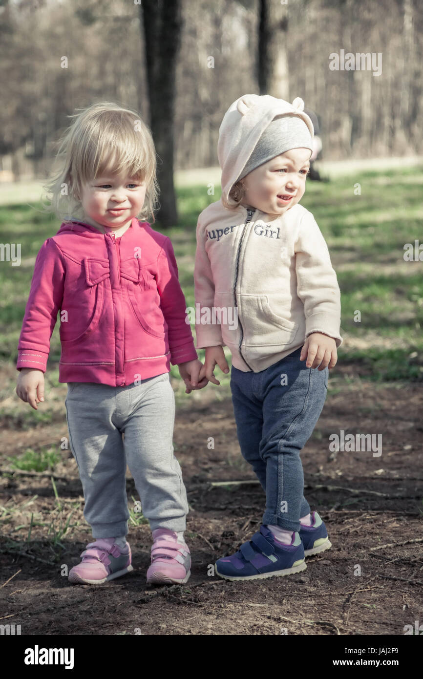 Due splendidi bambini ragazze che tiene insieme con le mani in estate park che simboleggiano i bambini amicizia e infanzia Foto Stock