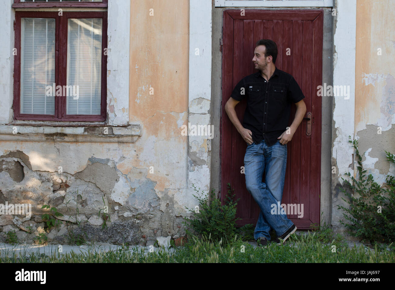 Uomo e una città. L'uomo è in piedi per appoggiarsi contro la porta. Foto Stock