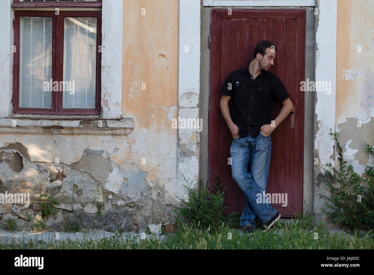 Uomo e una città. L'uomo è in piedi per appoggiarsi contro la porta. Foto Stock