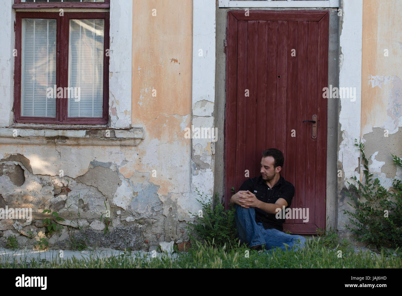 Uomo e una città. L'uomo è la localizzazione di appoggiarsi contro la porta. Foto Stock