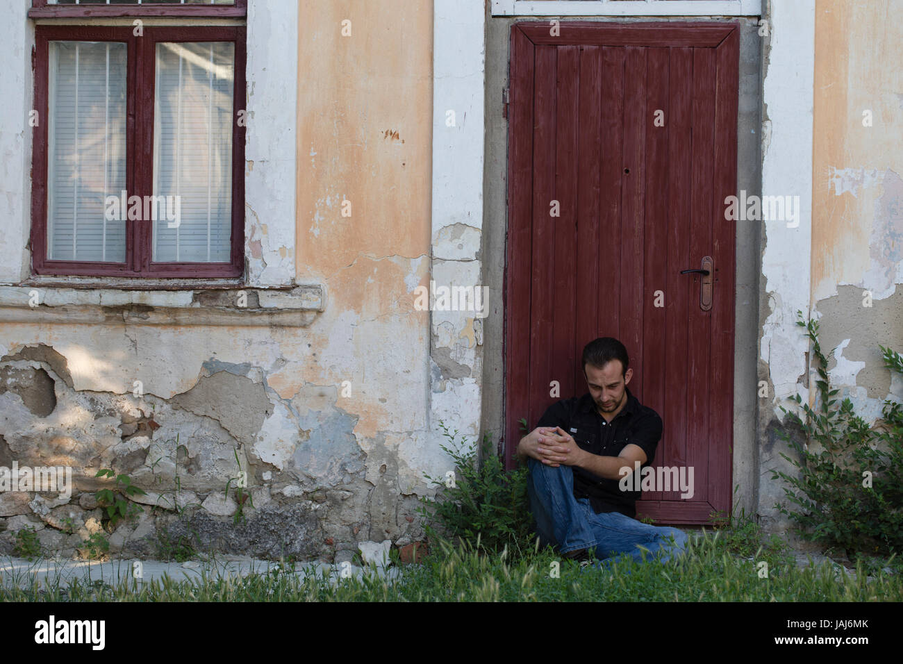 Uomo e una città. L'uomo è la localizzazione di appoggiarsi contro la porta. Foto Stock