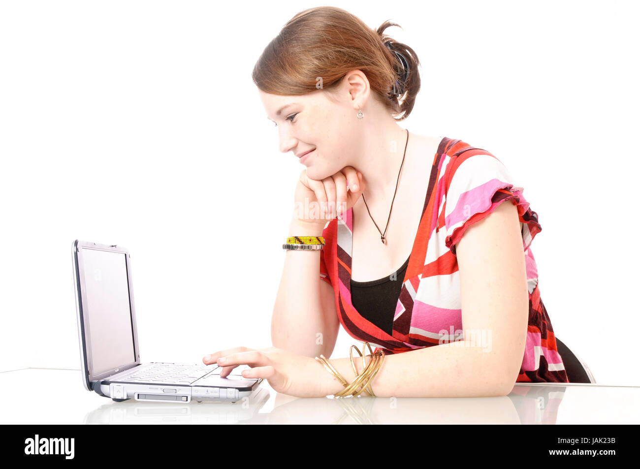 Mädchen, Schülerin sitzt am Schreibtisch und arbeitet am Laptop vor weißem Hintergrund. Foto Stock