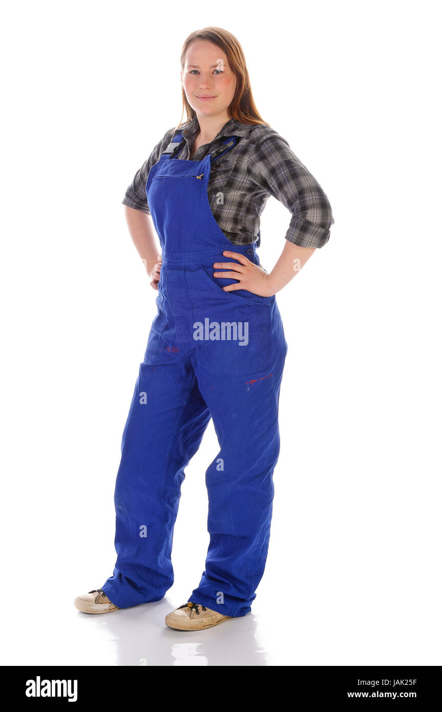 Junge Frau (Handwerkerin, Heimwerkerin, Auszubildende) mit langen Haaren trägt eine karierte Bluse und eine blaue Arbeits-Latzhose vor weißem Hintergrund. Sie posiert stolz und zufrieden vor der Kamera Foto Stock
