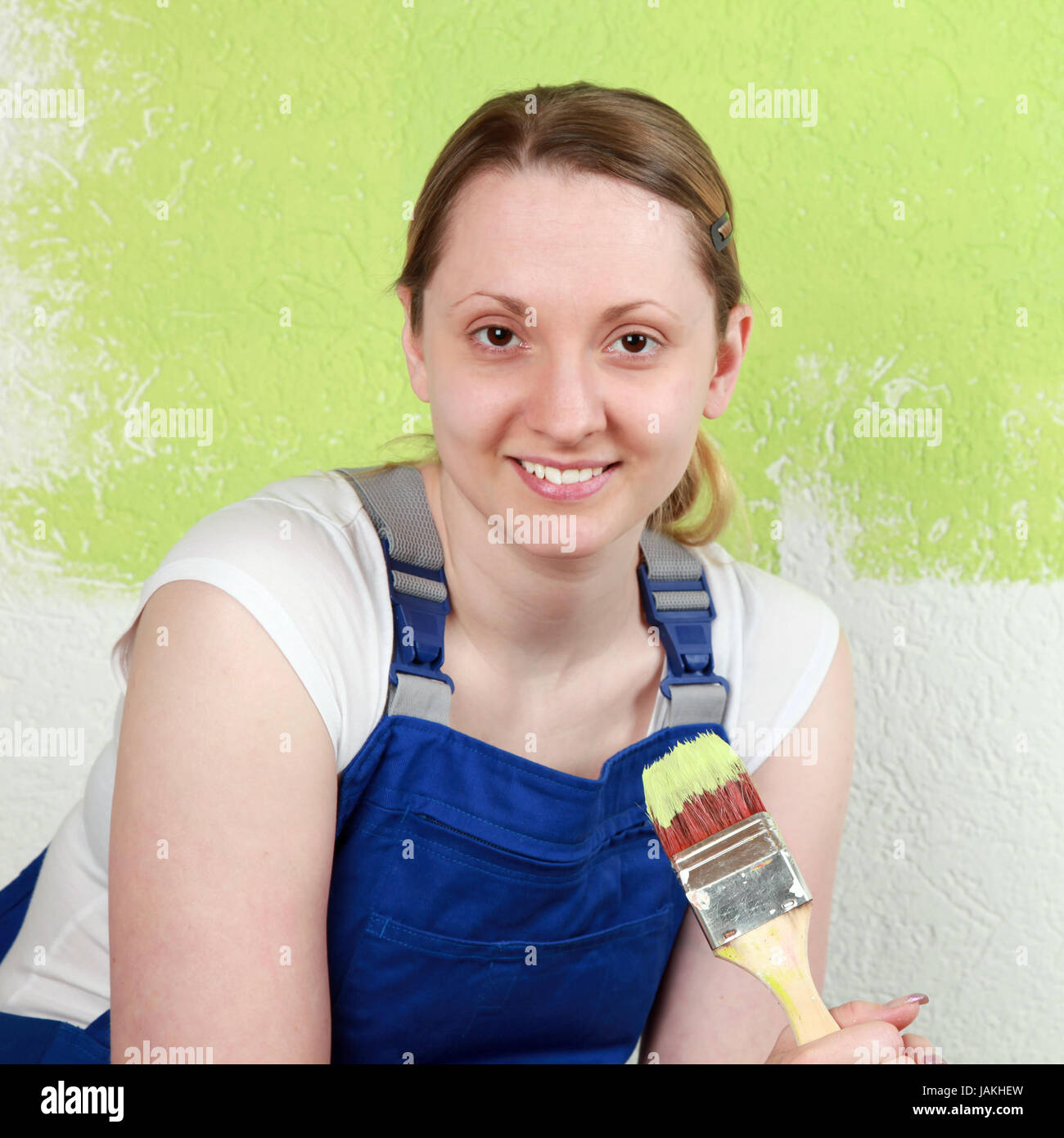 Eine glückliche Frau streicht eine Wand Mit einem Pinsel Foto Stock