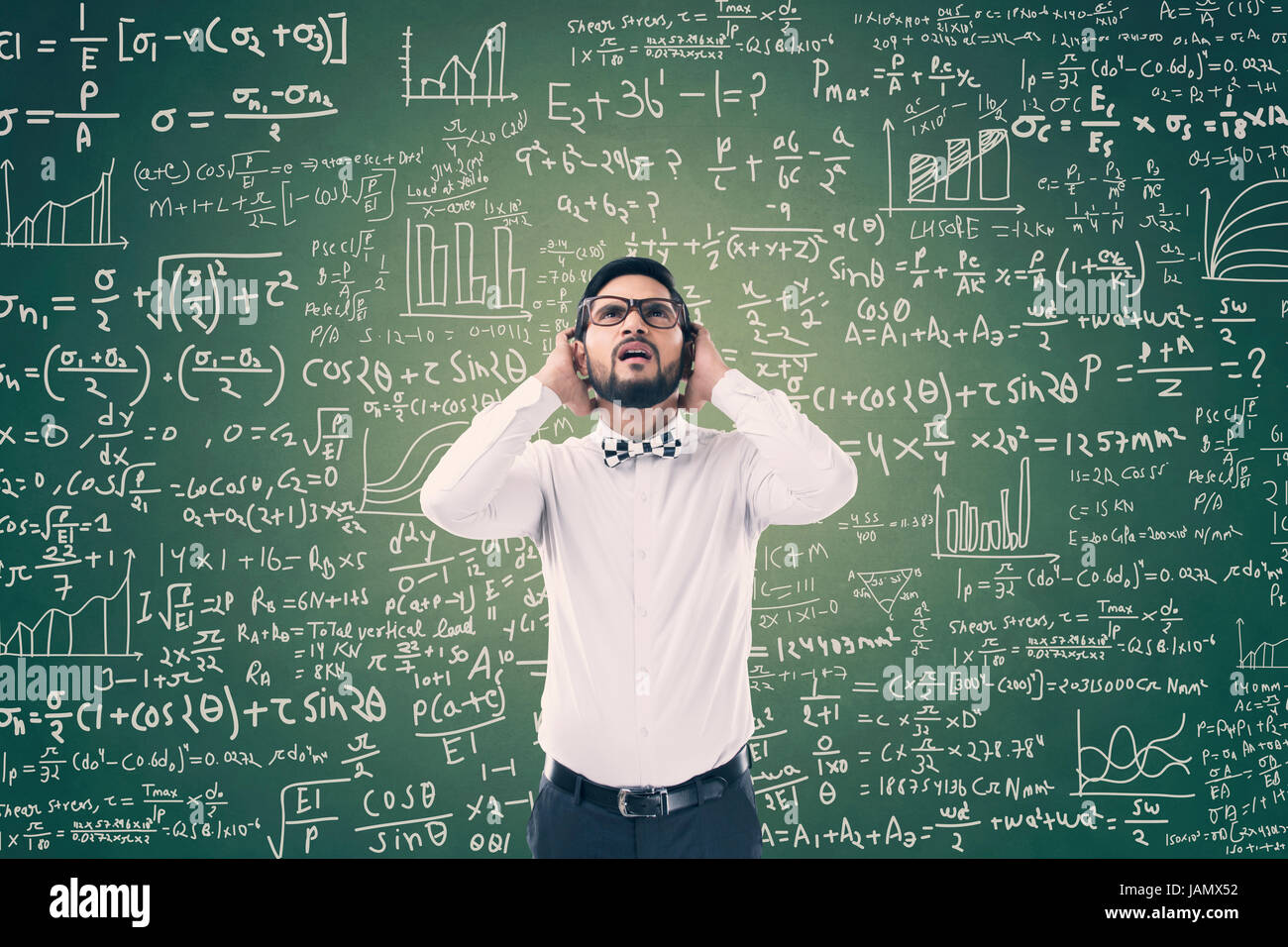 Giovane uomo risolvere equazione matematica sulla lavagna verde Foto Stock