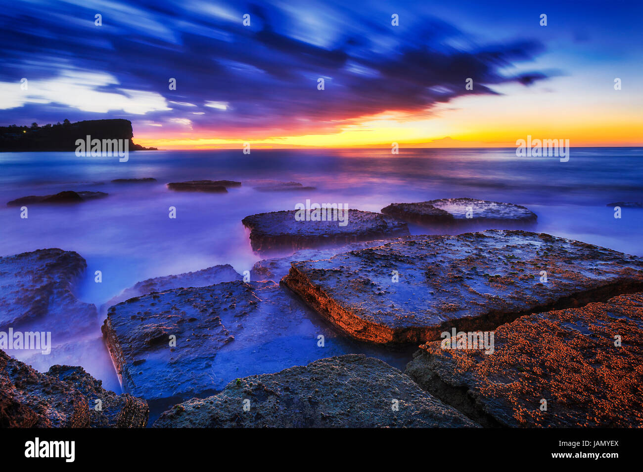 Blu scuro ora tramonto sul mare orizzonte a Avalon Beach rocce con alga di Nord di Sydney. Foto Stock