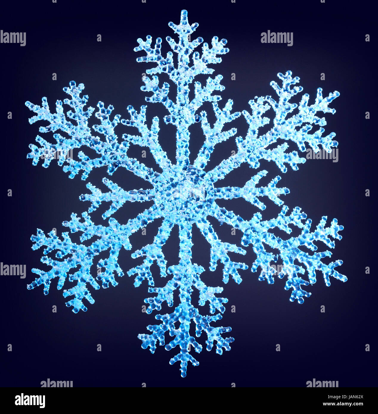 Illuminata in blu chiaro artificiale il simbolo del fiocco di neve in dark indietro Foto Stock