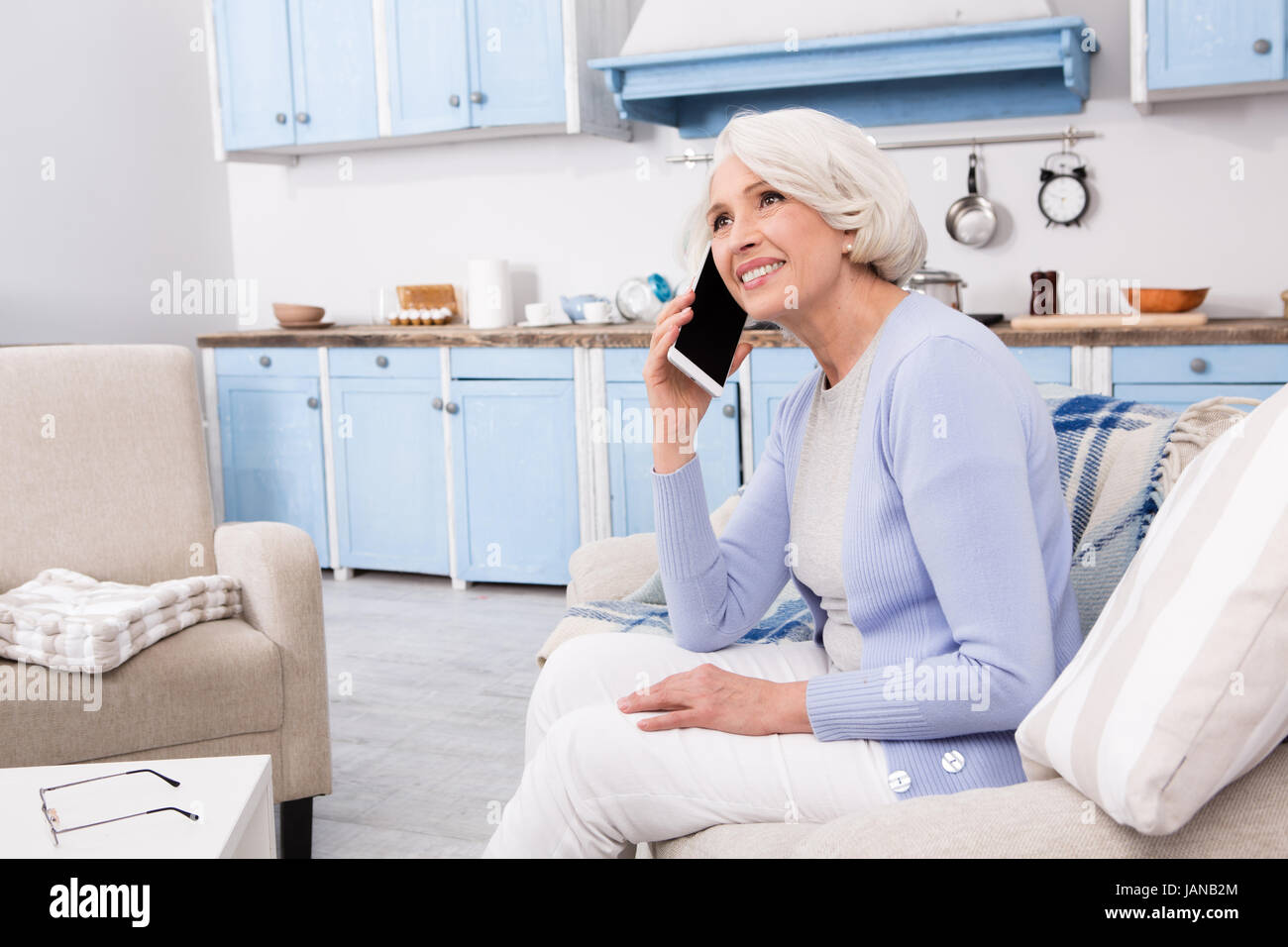 Donna anziana utilizzando il telefono cellulare a casa Foto Stock