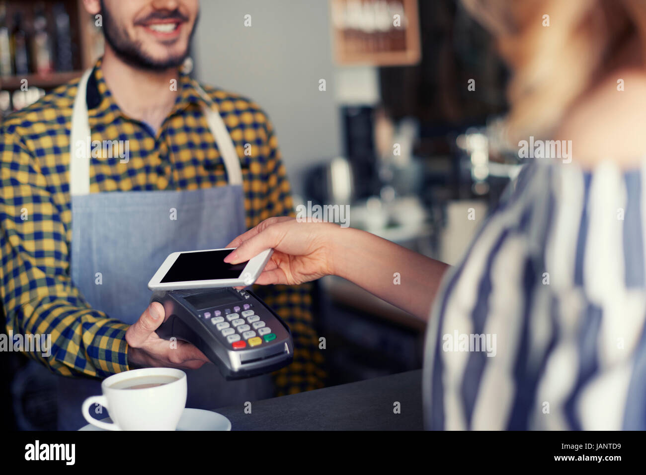 Cliente femmina pagando con la carta di credito per la tazza di caffè Foto Stock