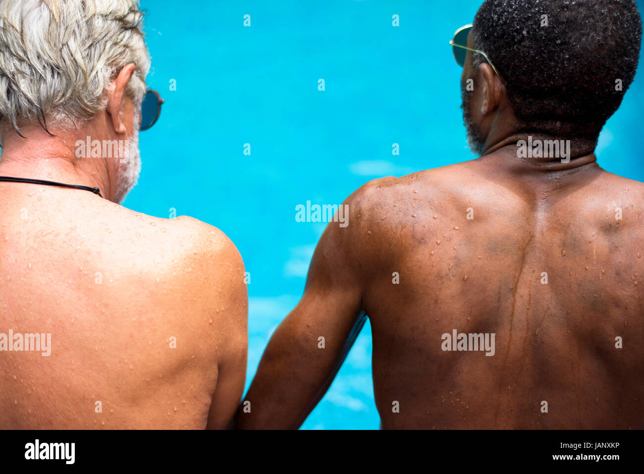 Vista posteriore di diverse senior adulti seduti a bordo piscina godendo di estate insieme Foto Stock