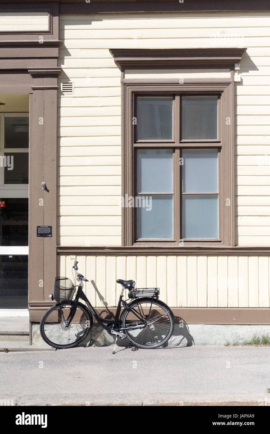 Bicicletta appoggiata a una tradizionale casa in legno alla luce del sole, nella Svezia centrale Foto Stock
