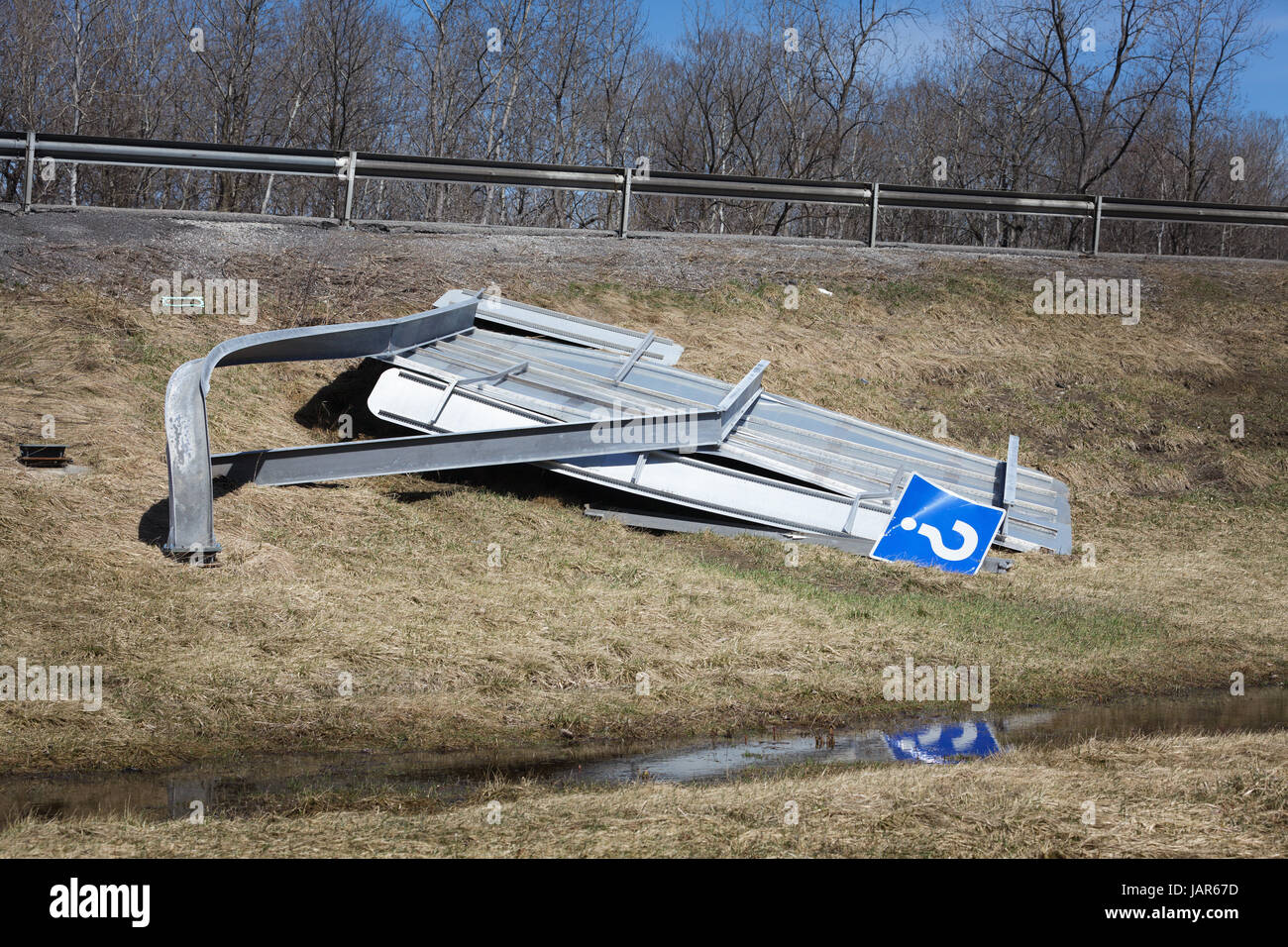 Canajoharie, New York Stati Uniti d'America - 9 Aprile 2017: un segno di traffico lungo la Interstate 90 stabilisce accartocciate sul terreno dopo essere stata distrutta dai forti venti. Foto Stock