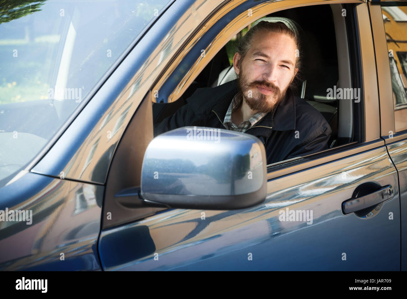 Barbuto grave uomo asiatico, driver del giapponese moderno suv crossover auto, ritratto all'aperto in aprire la finestra auto Foto Stock