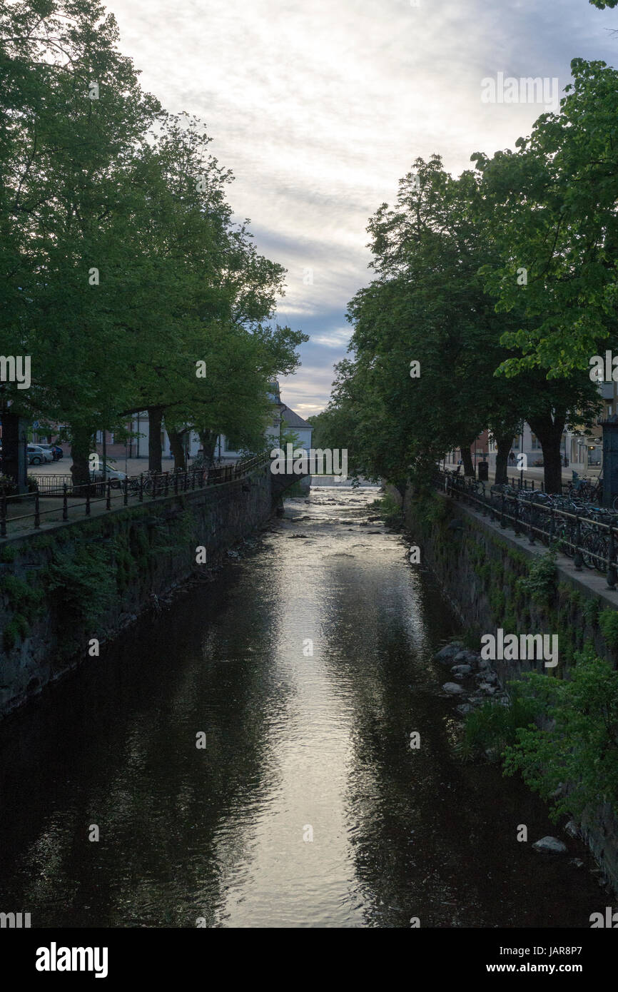 Tranquillo fiume che scorre attraverso il centro di Uppsala, Svezia, fiancheggiato da alberi ed edifici storici Foto Stock