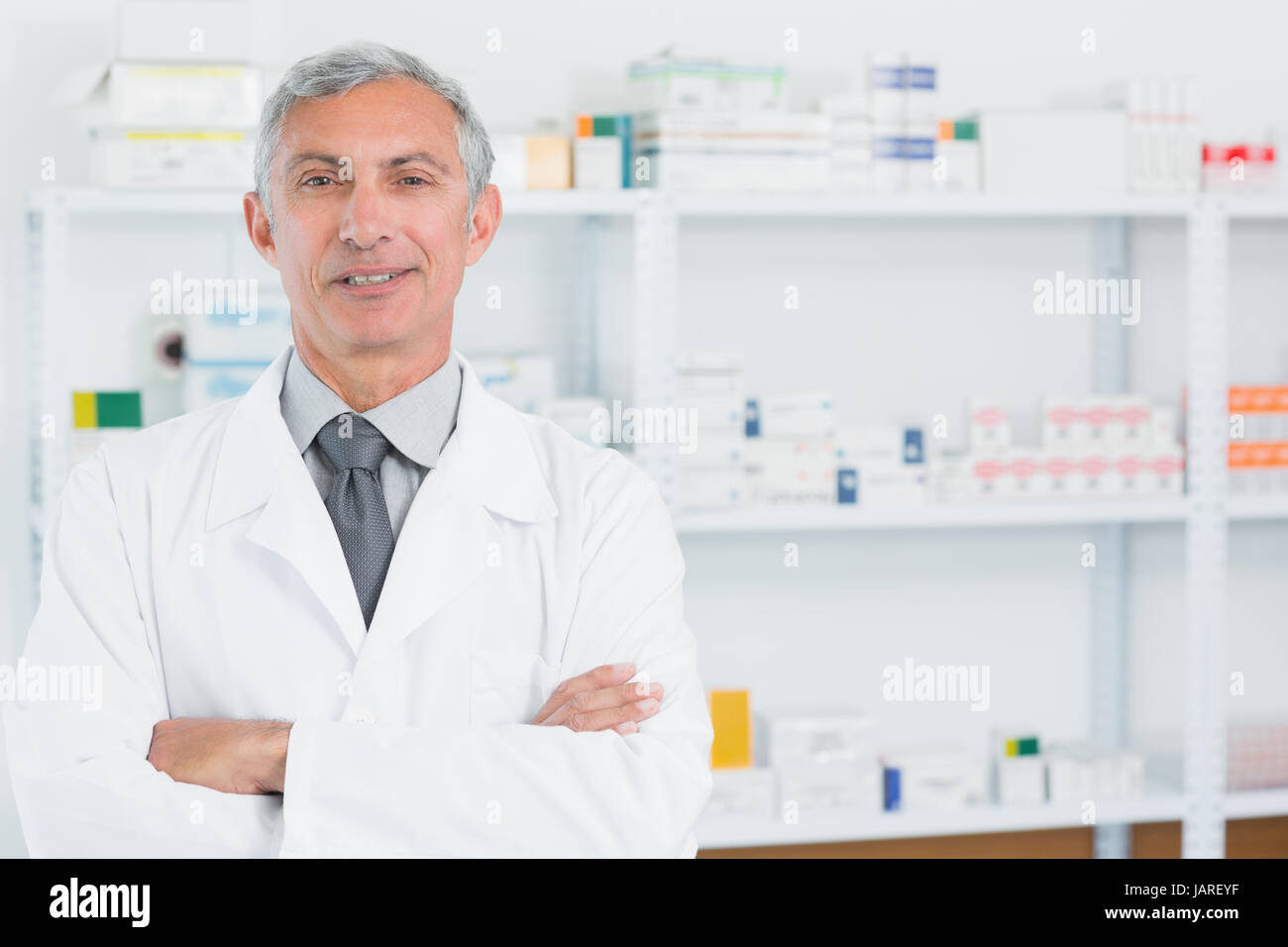 Il farmacista in piedi in una farmacia con le braccia incrociate in un ospedale Foto Stock
