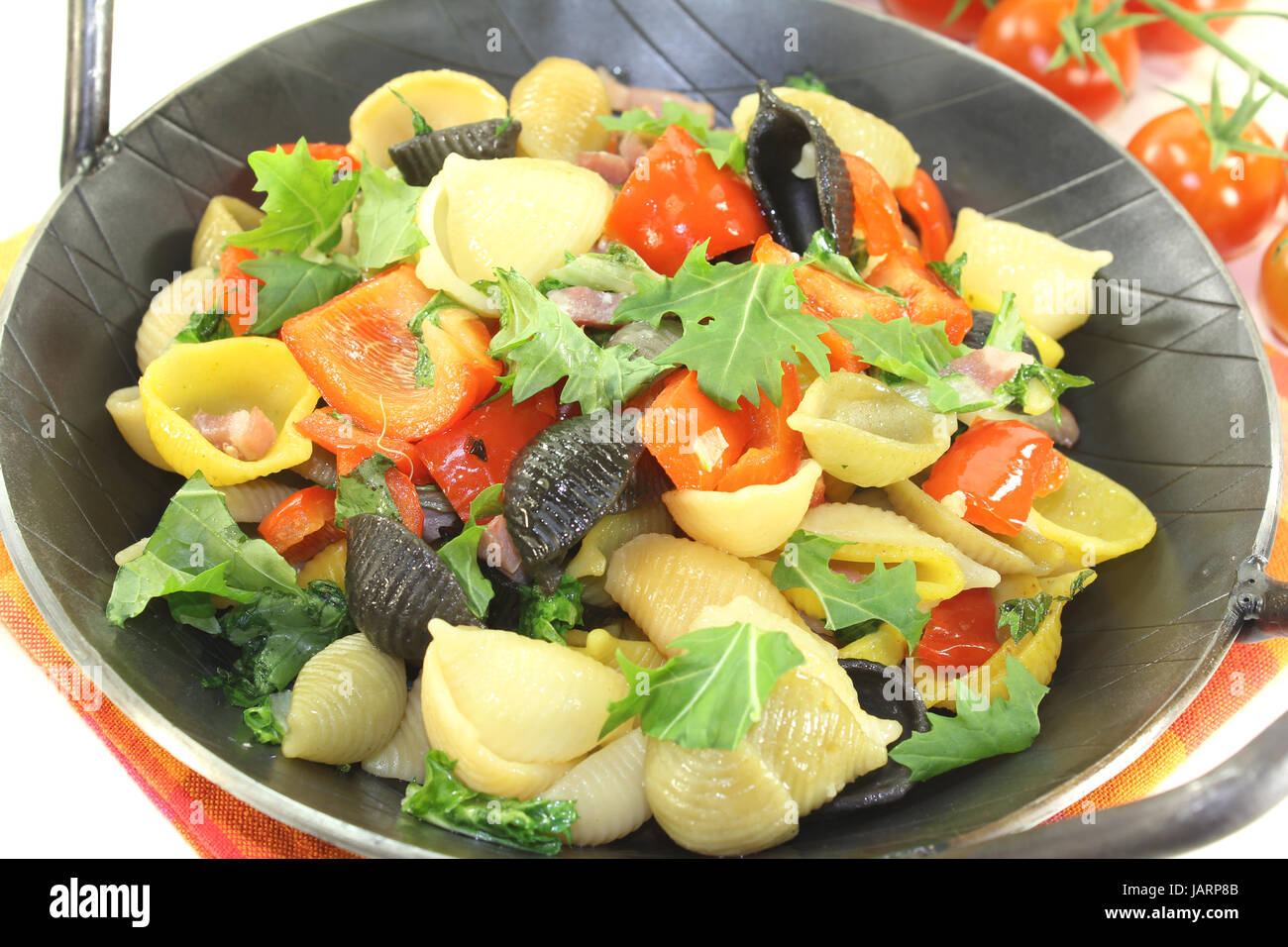 Nudelpfanne mit Paprika, Tomaten und Knoblauch vor hellem Hintergrund Foto Stock