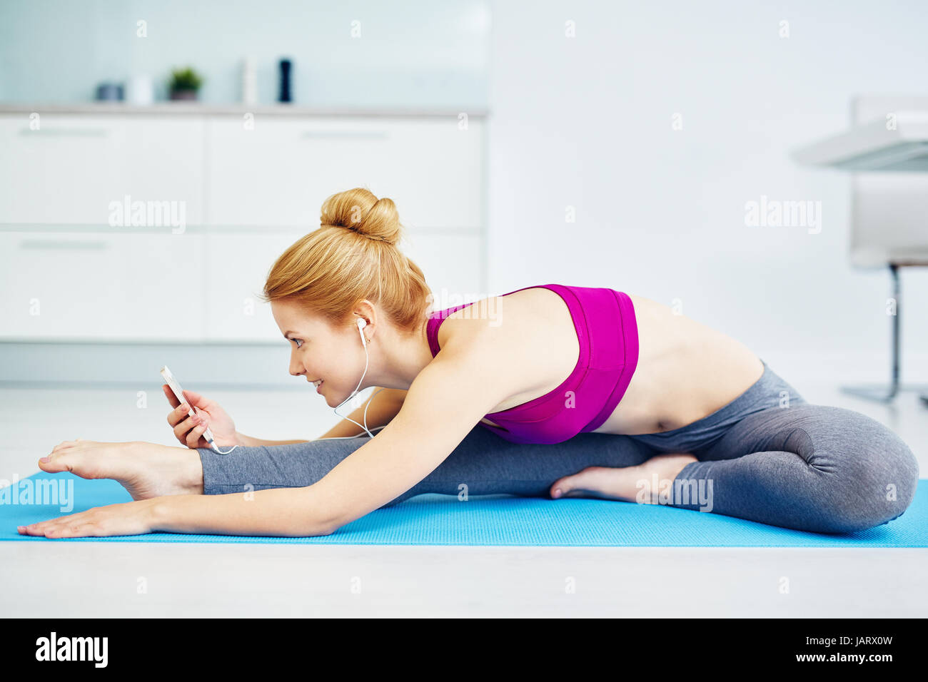 Sorridente giovane donna Stretching e ascolto di musica Foto Stock