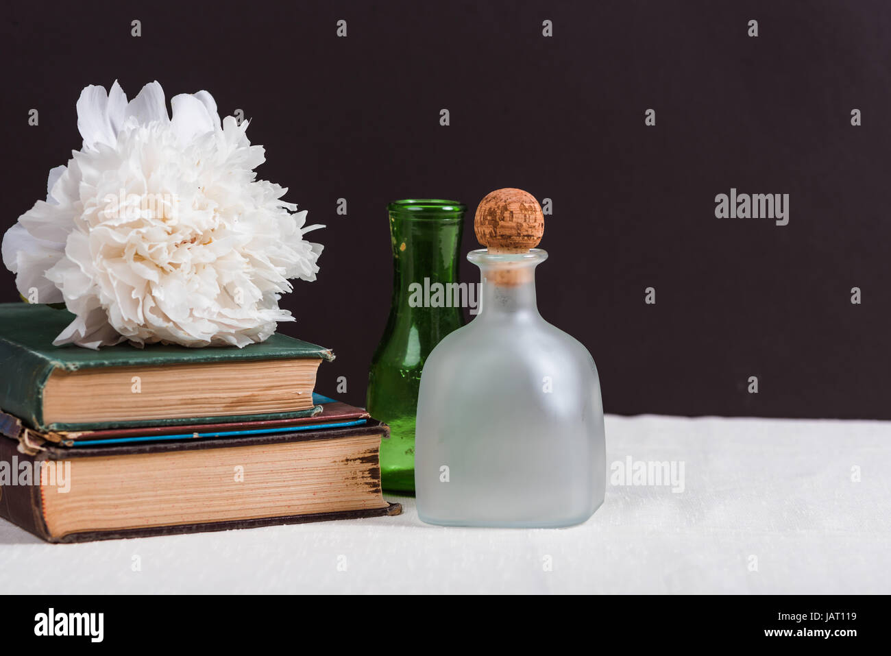 Vetreria Vintage accanto a vecchi libri con una peonia fiore Foto Stock