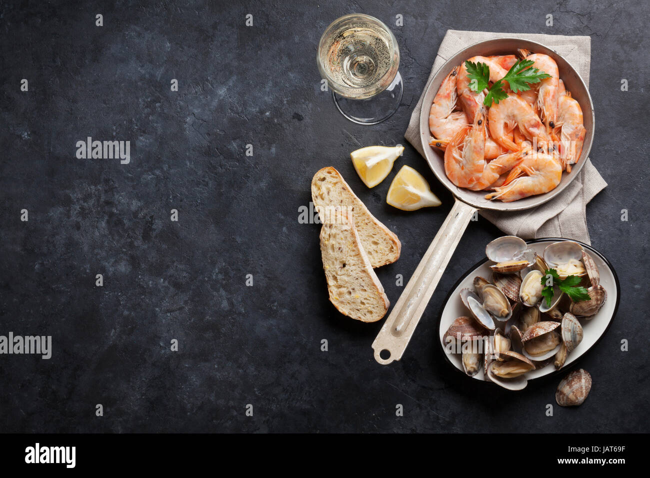 Piatti a base di pesce fresco e vino bianco sul tavolo di pietra. Cappesante e gamberetti. Vista da sopra con lo spazio di copia Foto Stock