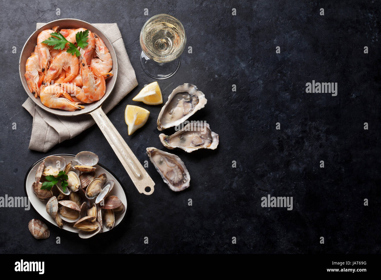 Piatti a base di pesce fresco e vino bianco sul tavolo di pietra. Capesante, Ostriche e gamberetti. Vista da sopra con lo spazio di copia Foto Stock