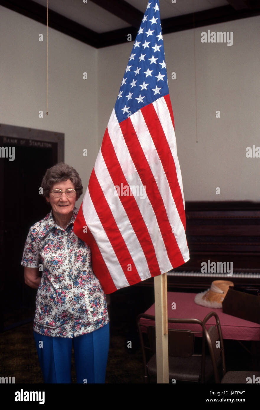Donna anziana che sta accanto ad una bandiera americana Foto Stock