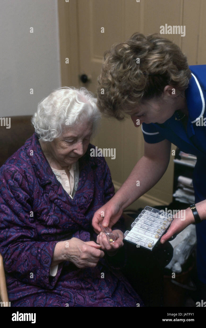 Distretto infermiere su una home visita ad assistere anziani donna con il suo farmaco quotidiano Foto Stock