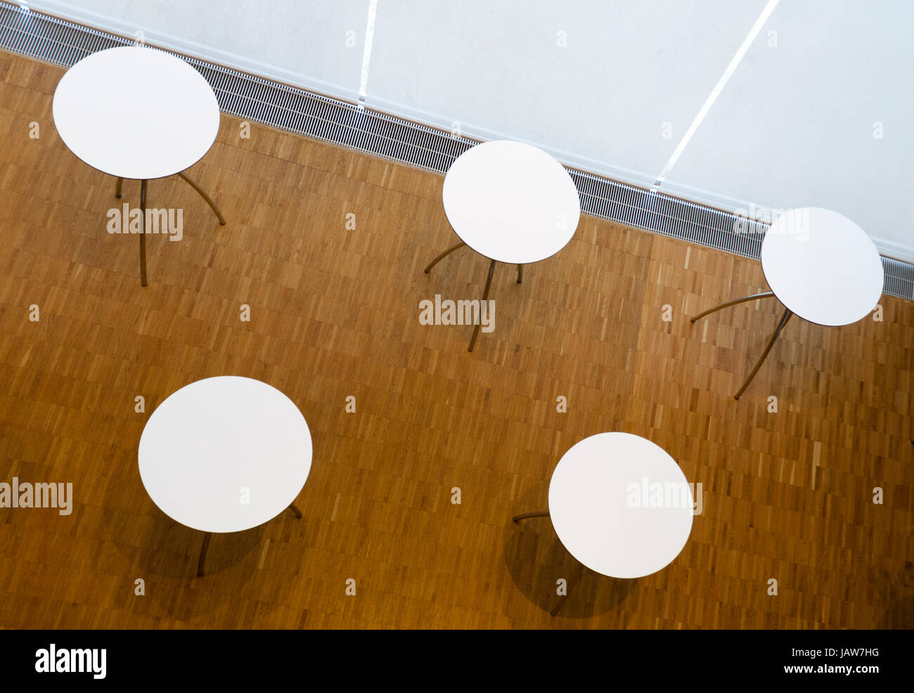 Blick von oben auf fünfTische mit weißer kreisförmiger Tischplatte und Parkettboden; vista dall'alto su cinque con tavola circolare bianco da tavolo e pavimento in parquet Foto Stock