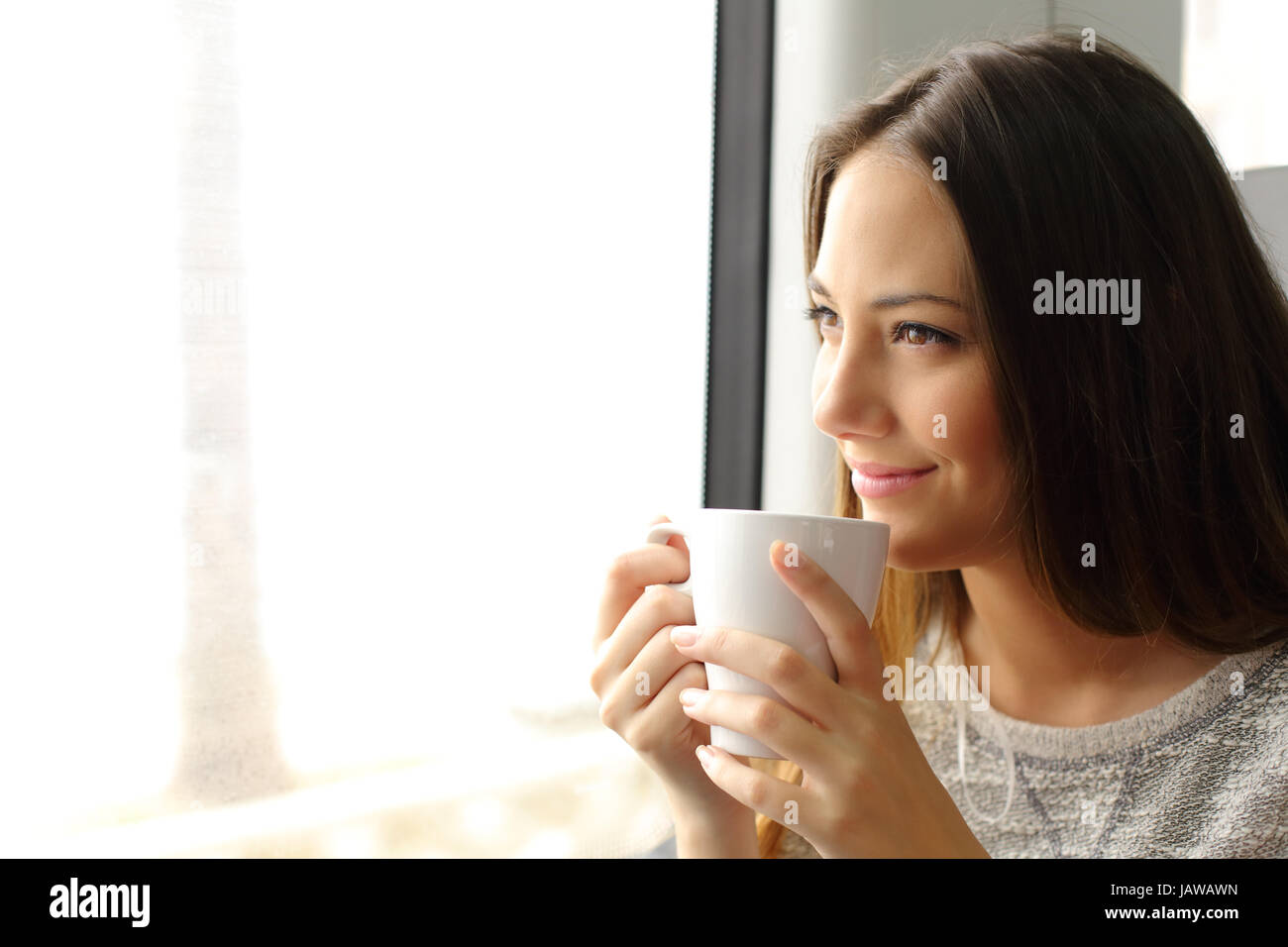 Felice pensieroso treno o autobus passeggero guardando attraverso la finestrella in possesso di una tazza di caffè Foto Stock