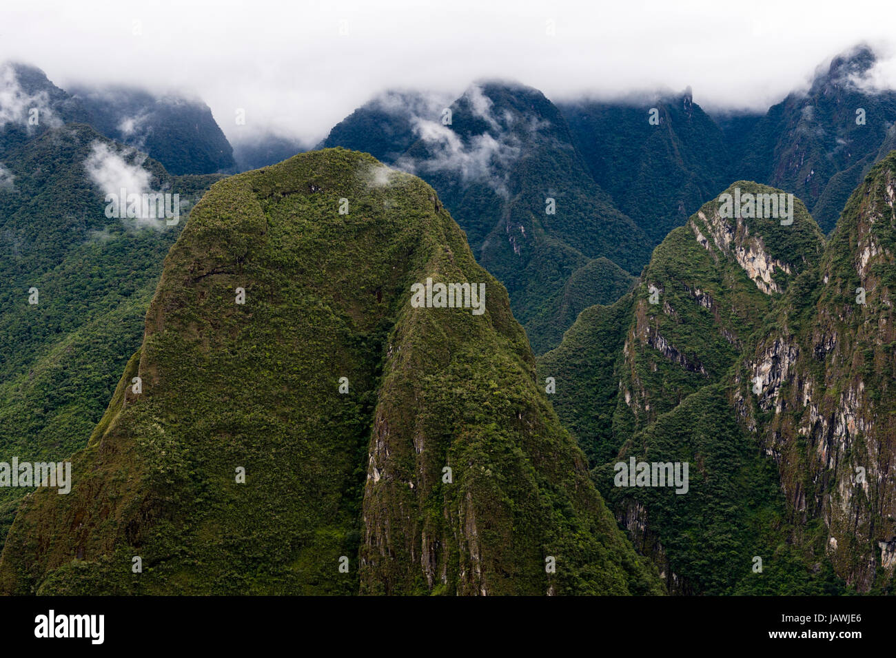 A picco sulle montagne coperte di foreste e cime frastagliate sopra valli profonde nelle Ande. Foto Stock
