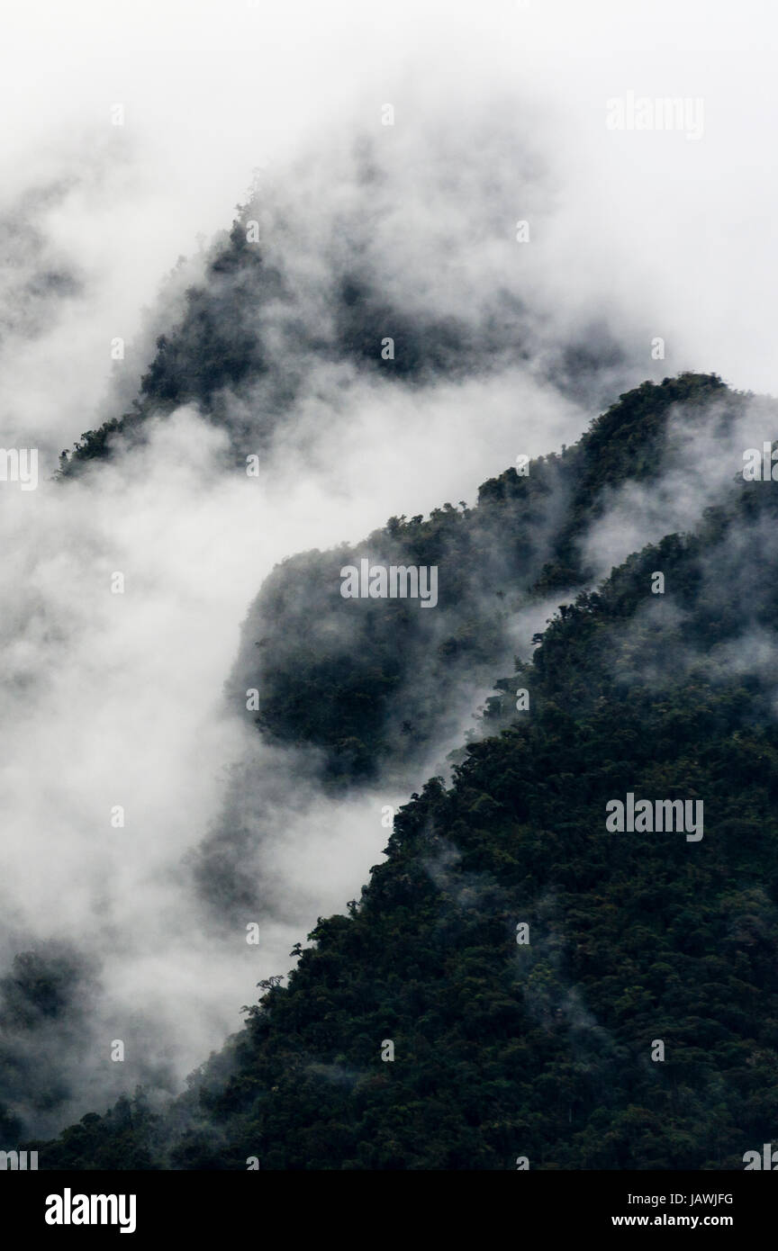 Nuvole temporalesche fagocitato le ripide pendici boscose e frastagliate cime delle montagne delle Ande. Foto Stock