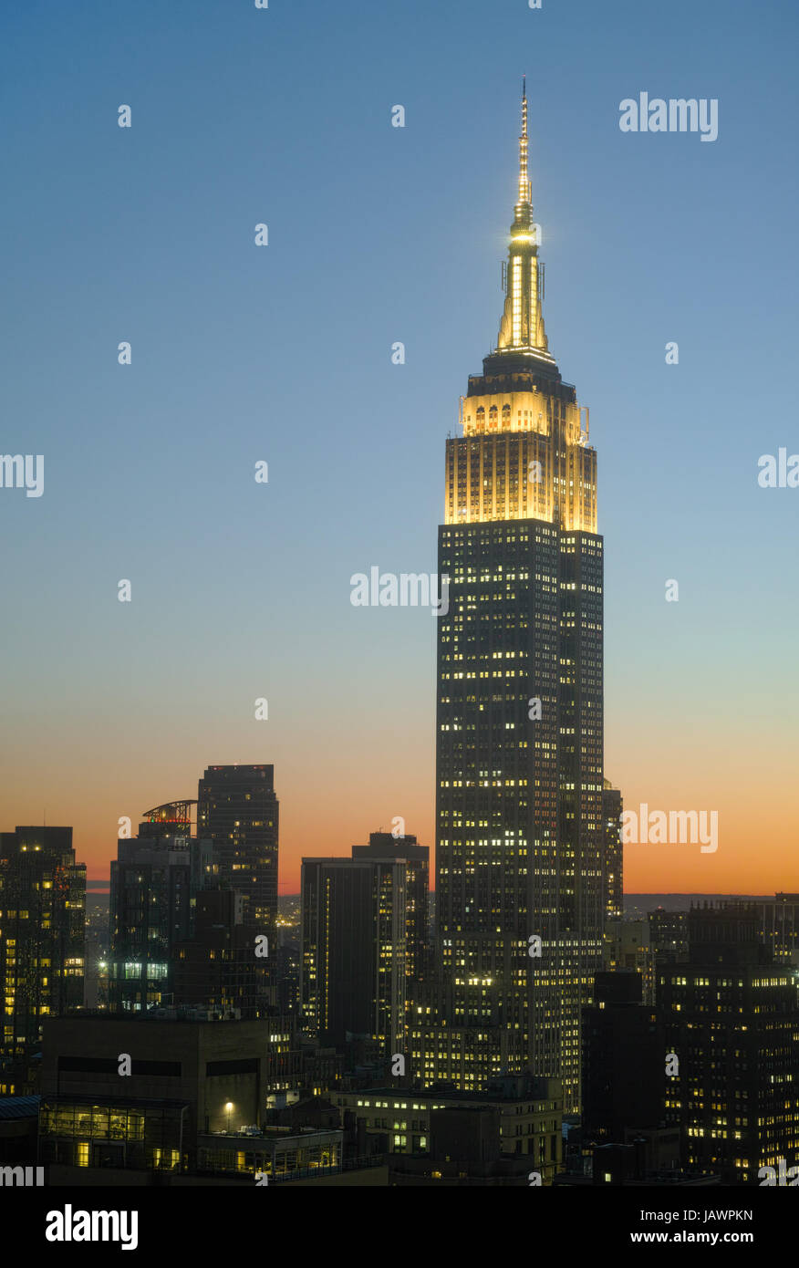Empire State Building al tramonto con il giallo delle luci della Torre in onore di giovani artisti e scrittori. Sagome scure di edifici vicini al di sotto di esso. - Giugno Foto Stock
