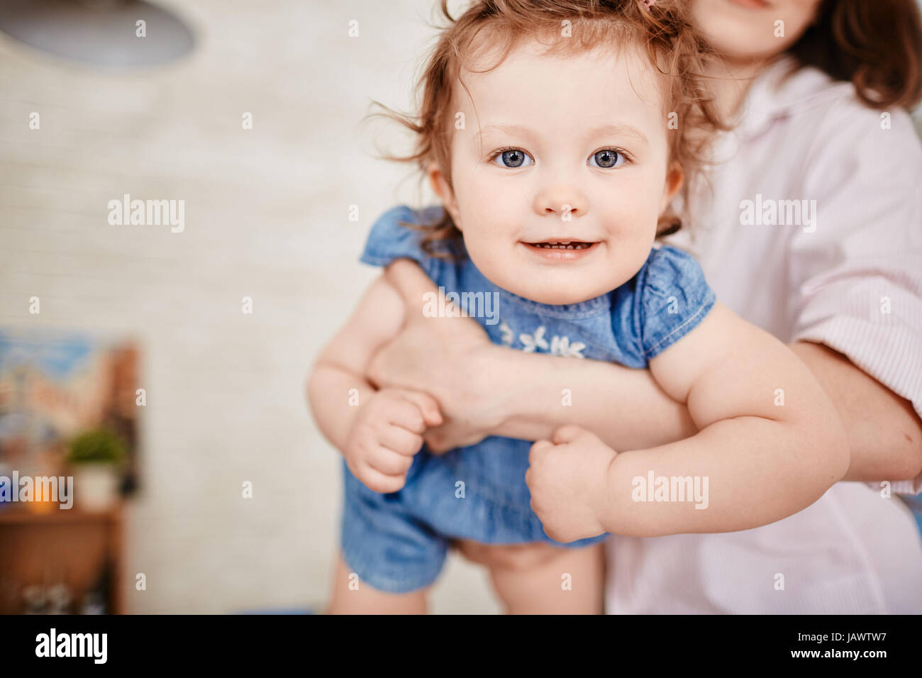 Angelic Bambina sui bracci delle madri Foto Stock